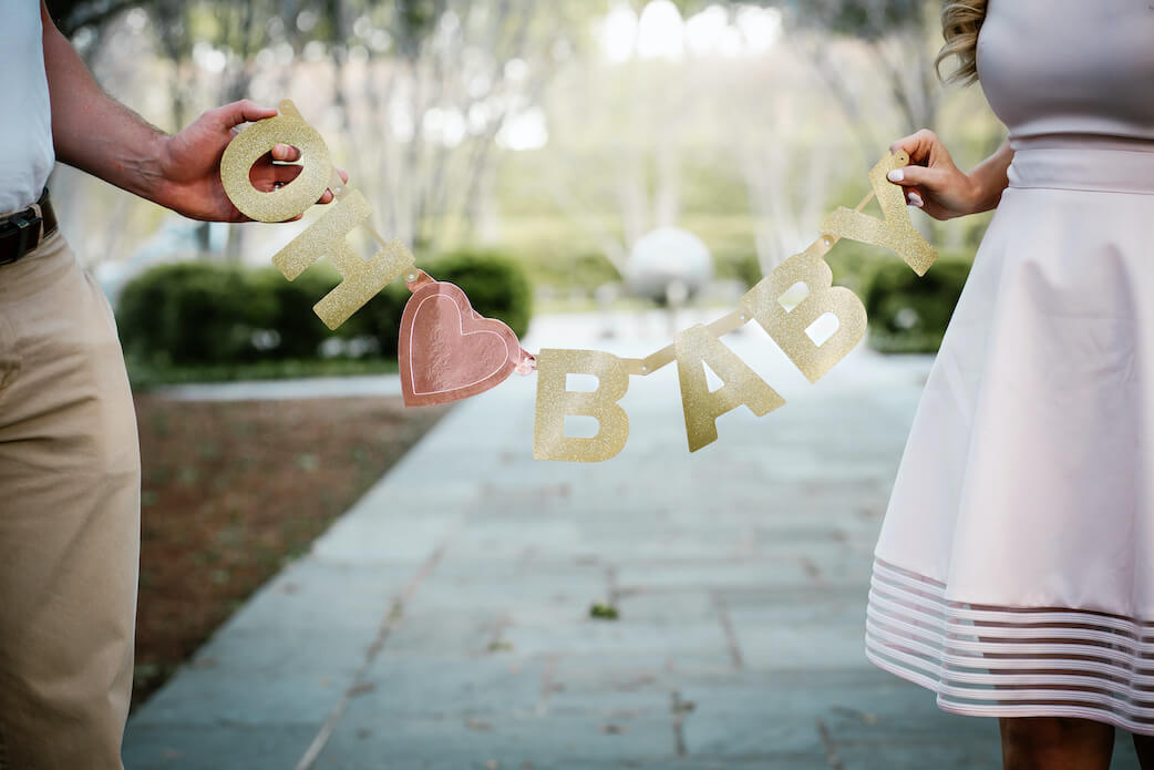 Schwangerschaft verkünden: Paar hält Girlande mit "Oh Baby" Schriftzug 