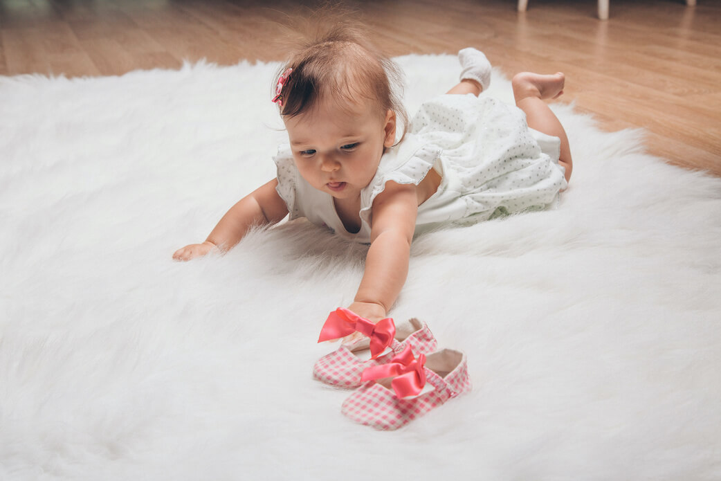 Baby mit neuen Babyschuhen als Geschenk zur Geburt