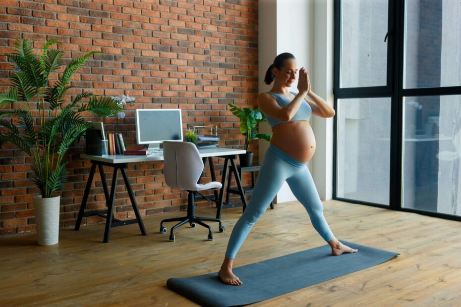 Schwangere Frau steht auf einer Matte und macht Yoga. 